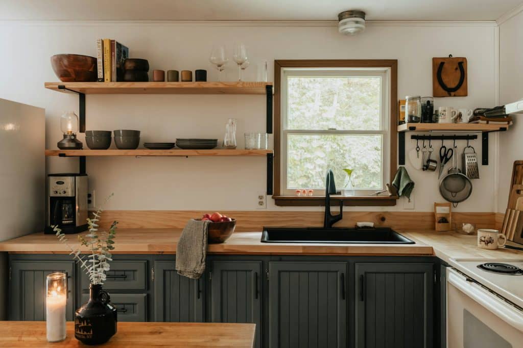 Peaceful minimalist kitchen with natural light, wooden counters, and organized shelving showing mindful living environment