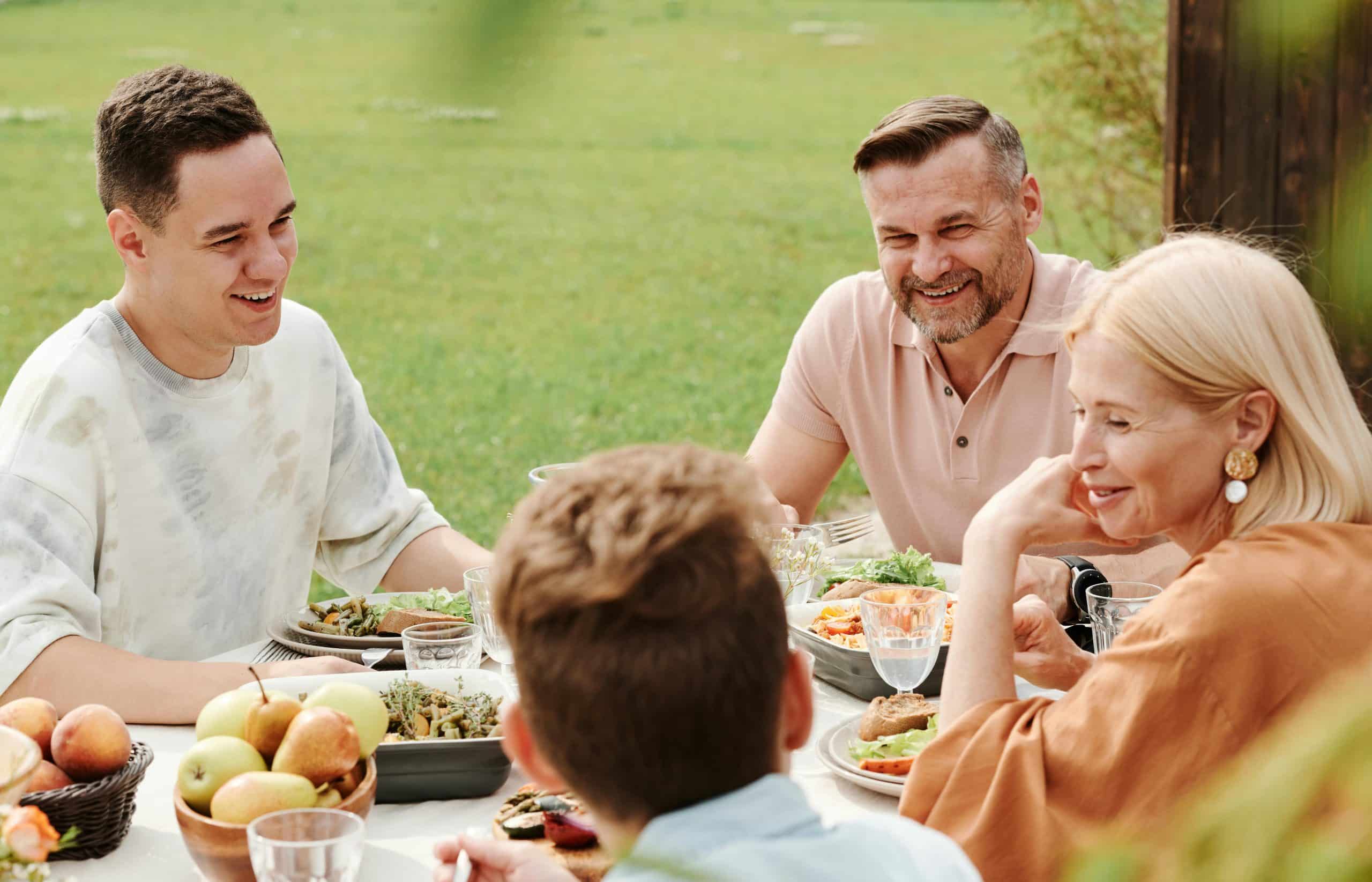 Family enjoying a healthy outdoor meal with fresh fruits and plant-based dishes, demonstrating the social aspects of Blue Zones lifestyle and longevity-promoting eating habits
