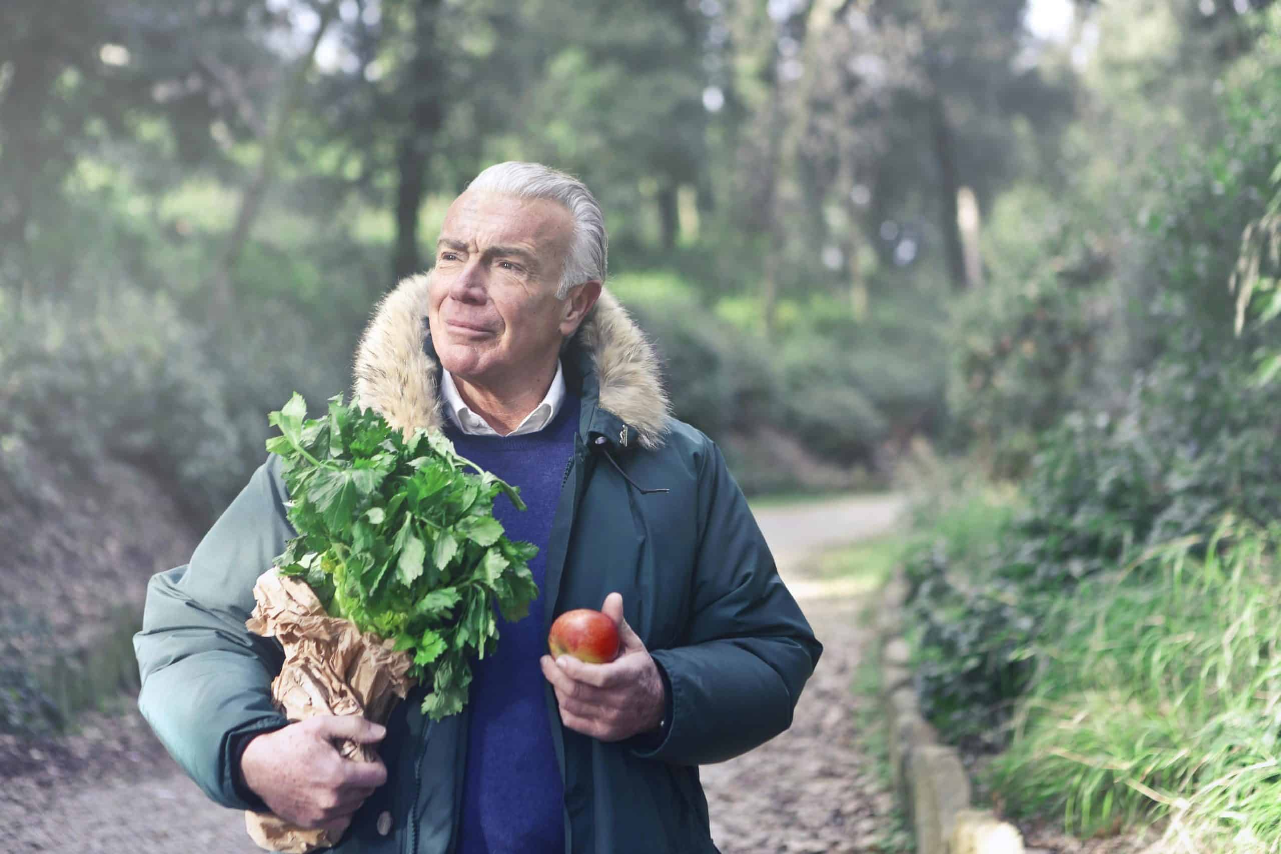 Elderly man tending to his vegetable garden, demonstrating the active lifestyle and plant-based diet common in Blue Zones regions. The centenarian maintains traditional farming practices that contribute to longevity.