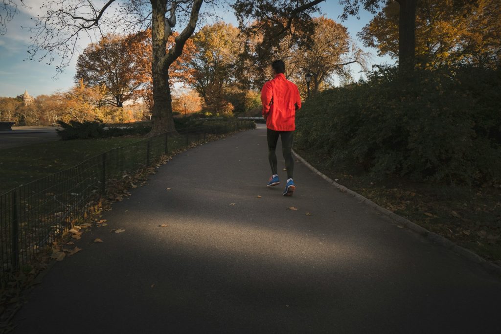 A person jogging in a park surrounded by trees and natural light symbolizes the connection between physical activity and improved mental clarity.