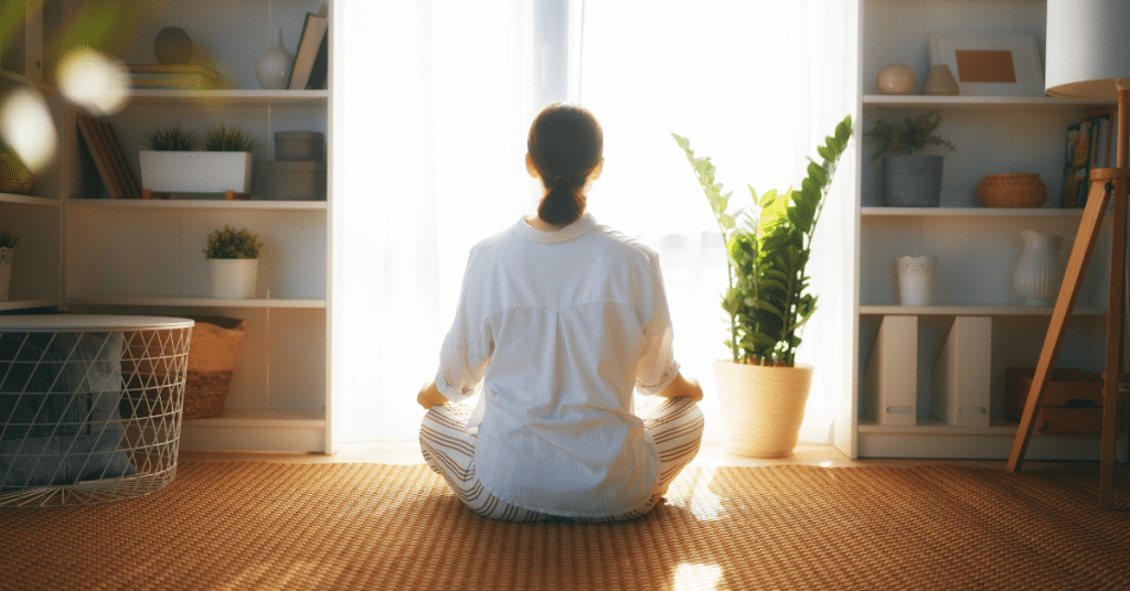 Person meditating in serene home environment with morning sunlight, demonstrating mindful approach to optimal aging