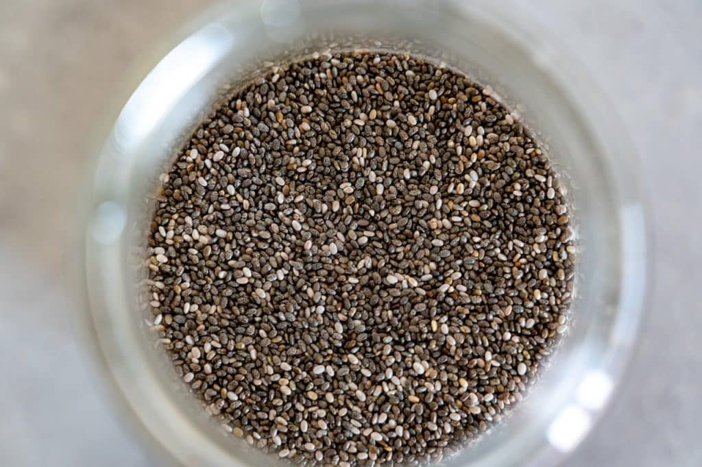 Close-up view of black and white chia seeds filling a white bowl, showing their distinctive speckled pattern