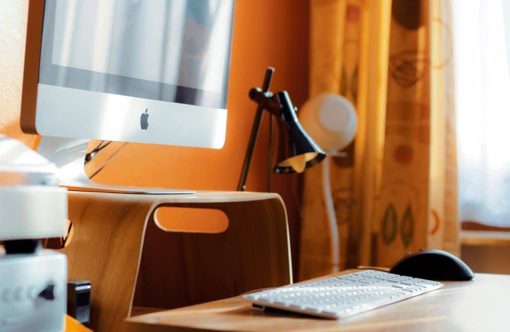 A minimalist desk setup with a computer, keyboard, and lamp symbolizes focus and an organized work environment.