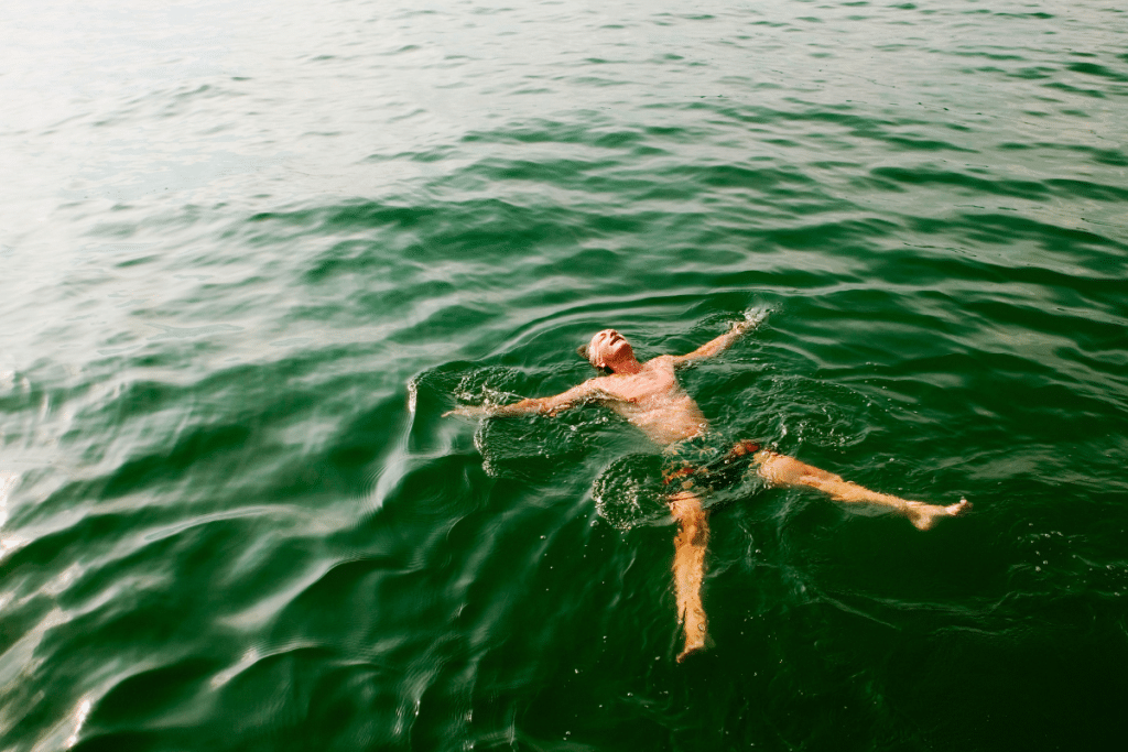 A relaxed person floating peacefully on their back in calm, natural water, demonstrating grounding through immersion.