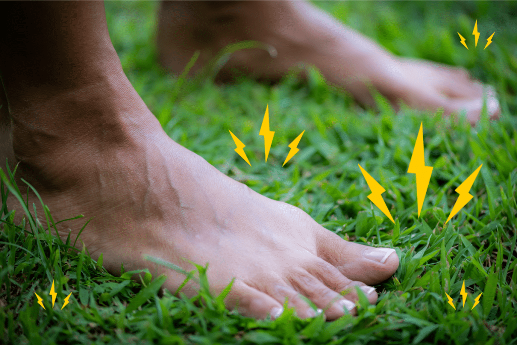 Bare feet standing on vibrant green grass, representing grounding and connection to Earth's energy.